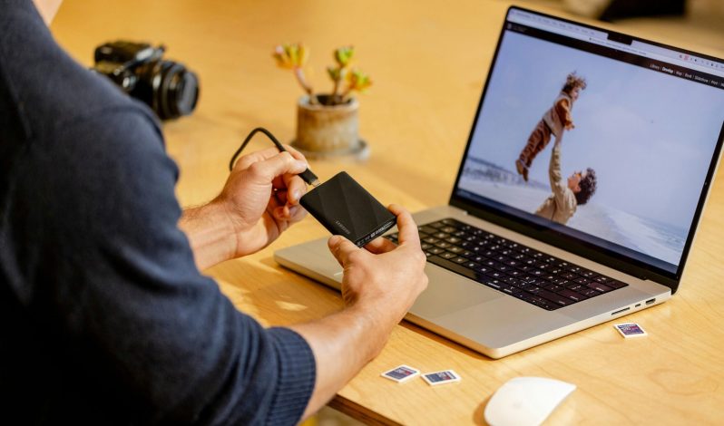 A man sitting at a table with a laptop and cell phone