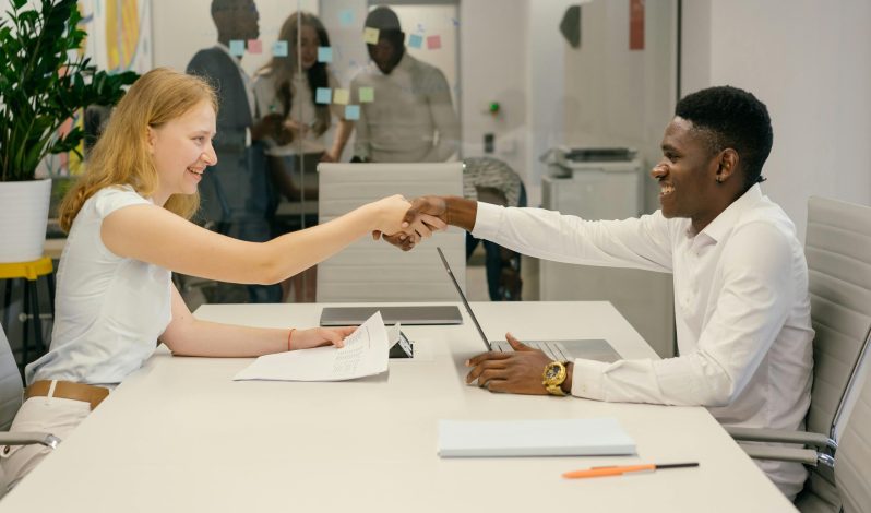 Free Business professionals completing a successful deal with a handshake in a modern office setting. Stock Photo